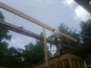Carpenter setting a ridge beam over a new addition frame — Ice Dam Removal by Roofing Brothers in Hot Springs